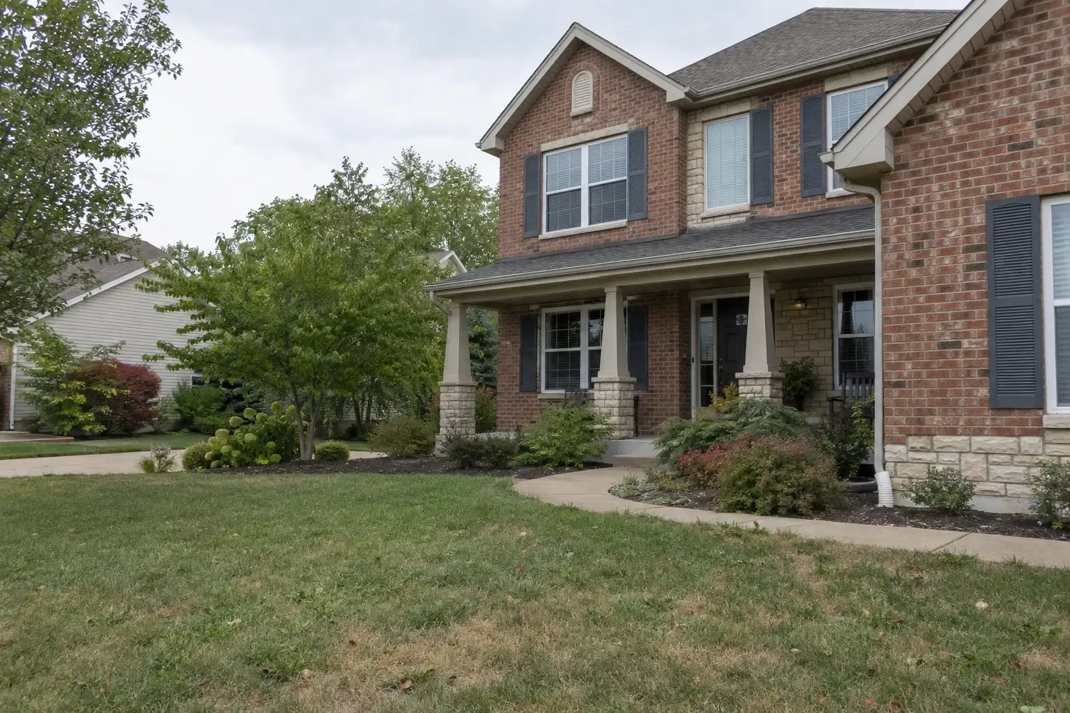 Two-story brick home with limestone accents and a covered front porch in a Missouri suburb