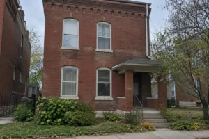 Older two-story red brick house with arched windows and decorative brickwork near the roofline